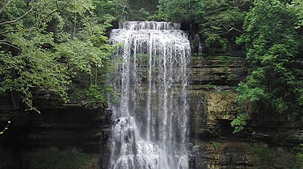 Tall waterfall in front of sheer limestone wall