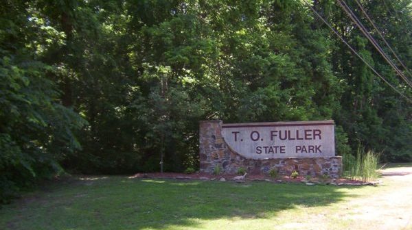 Stone sign reading "T. O. Fuller State Park" at the edge of wooded area