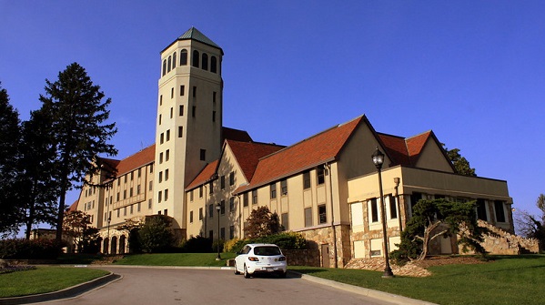 Large college building in limestone with red roof
