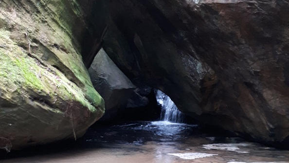 Stream flowing under large rocks