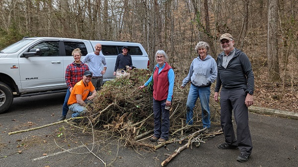 Several volunteers in front of a truck with a pile of invasive plants and shrubs