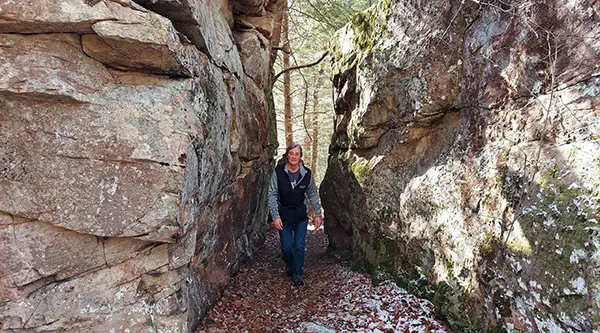 hiker on trail between huge boulders