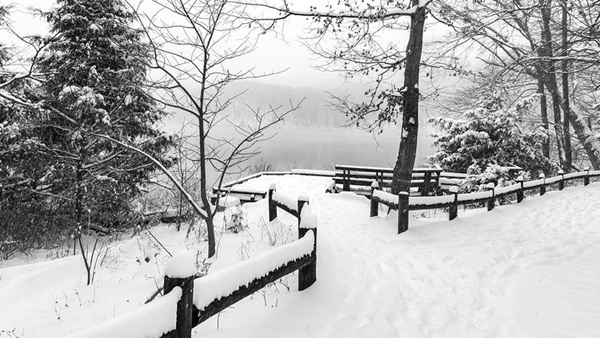 In the snow - an trail with wood fencing next to a lake