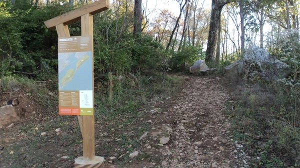 Trail kiosk on left with wooded trail on right